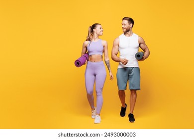 Full body young fun strong fitness trainer sporty two man woman wear blue clothes spend time in home gym hold yoga mat look to each other isolated on plain yellow background. Workout sport fit concept - Powered by Shutterstock