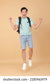 Full Body Of A Young Handsome Asian Male Student, Jump Over The Space, With Backpack And Isolated On Beige Background