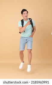 Full Body Of A Young Handsome Asian Male Student, Jump Over The Space, With Backpack And Isolated On Beige Background