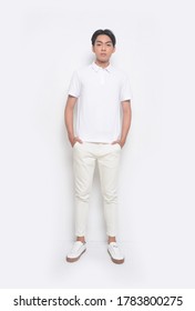 Full Body Young Handsome Man With Wearing White Polo Shirt With White Jeans Pants Standing Hands In Pockets 

