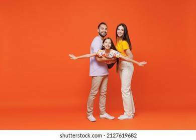 Full Body Young Happy Cheerful Parents Mom Dad With Child Kid Daughter Teen Girl In Basic T-shirts Hold Carrying Baby With Outstretched Hands Like Fly Isolated On Yellow Background. Family Day Concept