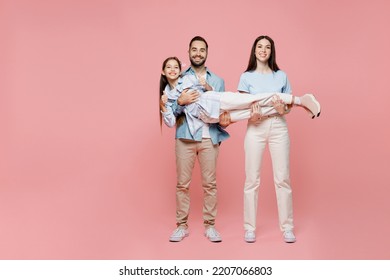 Full Body Young Happy Cherful Cool Parents Mom Dad With Child Kid Daughter Teen Girl In Blue Clothes Hold Kid Look Camera Have Fun Isolated On Plain Pastel Light Pink Background. Family Day Concept