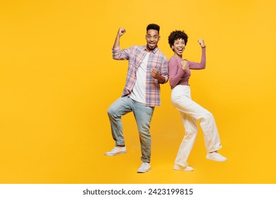 Full body young happy couple two friends family man woman of African American ethnicity wear purple casual clothes together do winner gesture clench fist rejoicing isolated on plain yellow background - Powered by Shutterstock