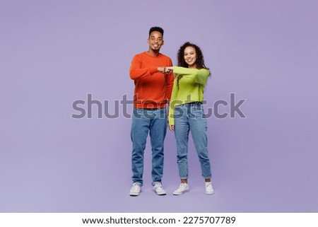 Full body young happy couple two friends family man woman of African American ethnicity wearing casual clothes together meet each other give fist bump isolated on pastel plain light purple background