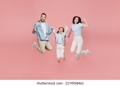 Full Body Young Happy Fun Parents Mom Dad With Child Kid Daughter Teen Girl In Blue Clothes Jump High Do Winner Gesture Clench Fist Isolated On Plain Pastel Light Pink Background. Family Day Concept