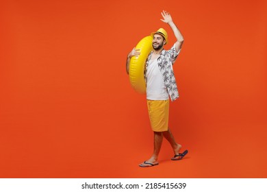 Full body young happy fun cool tourist man wear beach shirt walking going hold inflatable ring waving hand isolated on plain orange background studio portrait. Summer vacation sea rest sun tan concept - Powered by Shutterstock