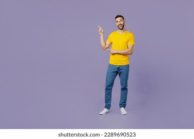 Full body young happy fun cool caucasian man wear yellow t-shirt point index finger aside indicate on workspace area copy space mock up isolated on plain pastel light purple background studio portrait - Shutterstock ID 2289690523