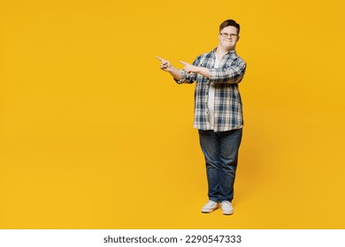 Full body young happy man with down syndrome wear glasses casual clothes point index fingers aside on workspace area isolated on pastel plain yellow color background. Genetic disease world day concept - Shutterstock ID 2290547333