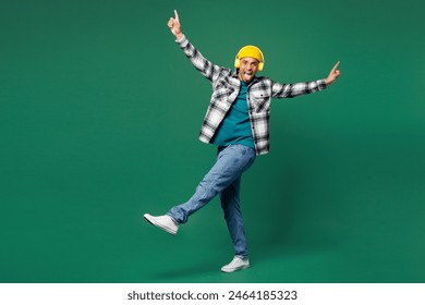 Full body young happy man of African American ethnicity he wear shirt blue t-shirt yellow hat listen to music in headphones spread hands isolated on plain green background studio. Lifestyle concept - Powered by Shutterstock