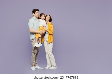 Full body young happy parents mom dad with child kid girl 6 years old wears blue yellow casual clothes hold daughter hugging cuddling embrace isolated on plain purple background. Family day concept - Powered by Shutterstock