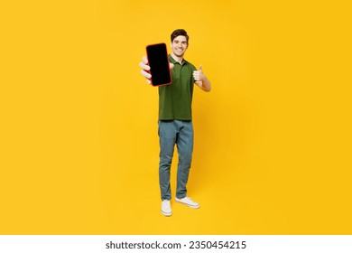 Full body young happy satisfied man he wears green t-shirt casual clothes hold in hand use close up mobile cell phone with blank screen workspace area show thumb up isolated on plain yellow background - Powered by Shutterstock