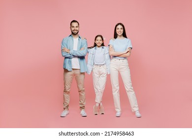 Full Body Young Happy Smiling Parents Mom Dad With Child Kid Daughter Teen Girl In Blue Clothes Hold Hands Crossed Folded Look Camera Isolated On Plain Pastel Light Pink Background. Family Day Concept