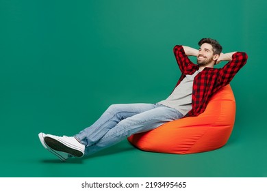 Full body young happy smiling fun man he 20s wearing red shirt grey t-shirt sit in bag chair hold hands crossed folded hold hands behind neck isolated on plain dark green background studio portrait. - Powered by Shutterstock