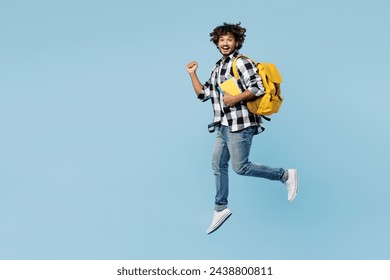 Full body young Indian boy student wear shirt casual clothes backpack bag hold books jump high do winner gesture isolated on plain pastel light blue background. High school university college concept - Powered by Shutterstock