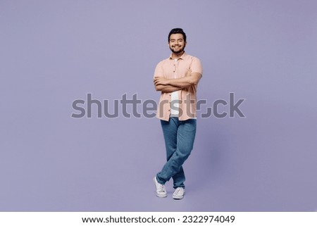 Full body young Indian man he wears pink shirt white t-shirt casual clothes hold hands crossed folded look camera isolated on plain pastel light purple background studio portrait. Lifestyle concept