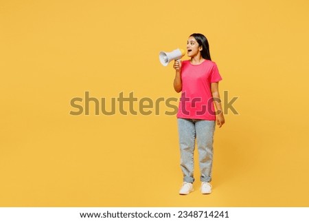 Full body young Indian woman wearing pink t-shirt casual clothes hold in hand megaphone scream announces discounts sale Hurry up isolated on plain yellow background studio portrait. Lifestyle concept