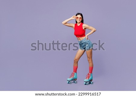 Full body young latin woman she wears red casual clothes rollers sunglasses rollerblading stand akimbo look camera isolated on plain pastel purple background. Summer sport lifestyle leisure concept