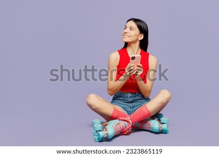 Full body young latin woman she wear red casual clothes rollers rollerblading hold in hand use mobile cell phone look aside isolated on plain purple background Summer sport lifestyle leisure concept
