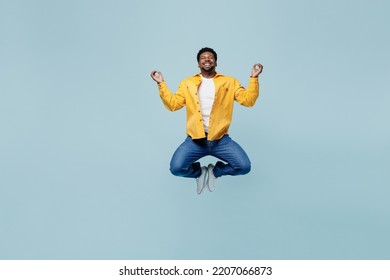 Full body young man of African American ethnicity wear yellow shirt jump high hold spreading hands in yoga om aum gesture relax meditate try to calm down isolated on plain pastel light blue background - Shutterstock ID 2207066873