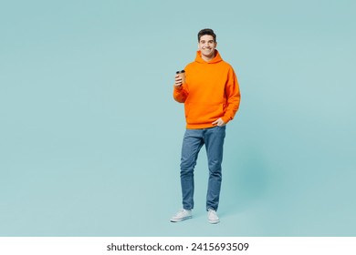 Full body young man he wears orange hoody casual clothes hold takeaway delivery craft paper brown cup coffee to go isolated on plain pastel light blue cyan color background studio. Lifestyle concept - Powered by Shutterstock