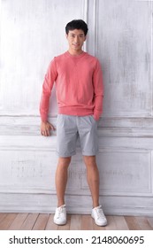 Full Body Young Man Wearing Orange Sweater With Gray Shorts Standing Posing In Studio