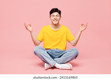 Full body young man wearing yellow t-shirt casual clothes sits hold spreading hands in yoga om aum gesture relax meditate try to calm down isolated on plain pastel pink background. Lifestyle concept - Powered by Shutterstock