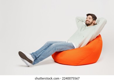 Full body young minded dreamful happy smiling man wear mint hoody sit in bag chair look camera hold hands behind neck isolated on plain solid white background studio portrait People lifestyle concept - Powered by Shutterstock