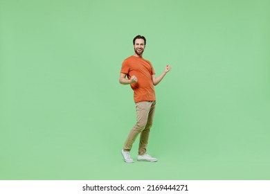 Full body young overjoyed excited happy cool fun man 20s wear casual orange t-shirt he do winner gesture isolated on plain pastel light green color background studio portrait. People lifestyle concept