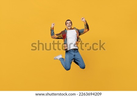 Full body young overjoyed excited happy middle eastern man 20s wear casual shirt white t-shirt jump high do winner gesture isolated on plain yellow background studio portrait People lifestyle concept