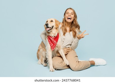 Full body young owner woman wear casual clothes sit hug cuddle embrace look at her best friend retriever dog in red bandana show v-sign isolated on plain blue background. Take care about pet concept - Powered by Shutterstock