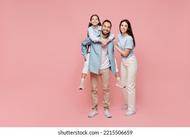 Full body young parents mom dad with child kid daughter teen girl in blue clothes giving piggyback ride to kid, sit on back isolated on plain pastel light pink background Family day childhood concept - Shutterstock ID 2215506659