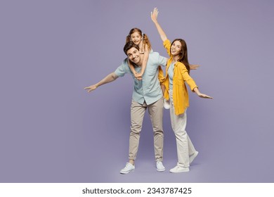 Full body young parents mom dad with child kid daughter girl 6 years old wear blue yellow casual clothes giving piggyback ride to joyful, sit on back spread hands isolated on plain purple background - Powered by Shutterstock