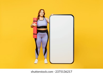 Full body young plus size big fat fit woman wear blue top warm up train big huge blank screen mobile cell phone hold yoga mat isolated on plain yellow background studio home gym. Workout sport concept - Powered by Shutterstock