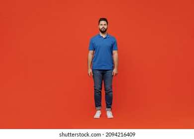 Full Body Young Serious Confident Calm Happy Caucasian European Attractive Man 20s Wear Basic Blue T-shirt Looking Camera Isolated On Plain Orange Background Studio Portrait. People Lifestyle Concept