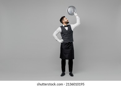 Full Body Young Smiling Barista Male Waiter Butler Man Wear White Shirt Vest Elegant Uniform Work At Cafe Hold In Hand Carrying Metal Tray Isolated On Plain Grey Background Restaurant Employee Concept