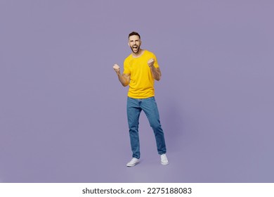 Full body young smiling caucasian man wears yellow t-shirt doing winner gesture celebrate clenching fists say yes isolated on plain pastel light purple background studio portrait. Lifestyle concept - Powered by Shutterstock