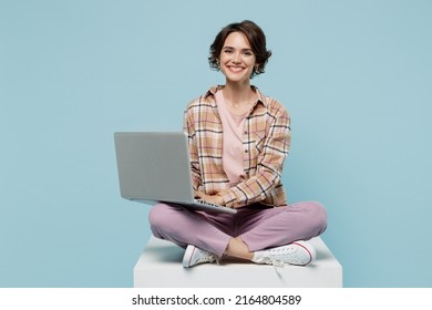 Full Body Young Smiling Cheerful Happy Cool Woman 20s Wearing Brown Shirt Sit On White Chair Hold Use Work On Laptop Pc Computer Isolated On Pastel Plain Light Blue Background People Lifestyle Concept