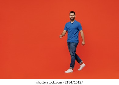 Full Body Young Smiling Fun Confident Calm Happy European Caucasian Man 20s Wear Basic Blue T-shirt Walking Going Stroll Isolated On Plain Orange Background Studio Portrait. People Lifestyle Concept