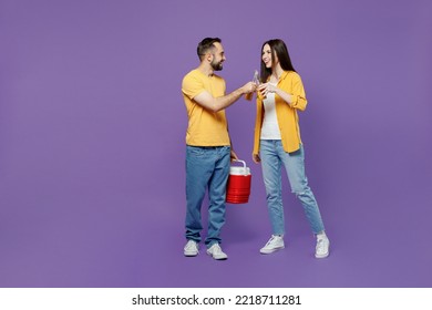 Full Body Young Smiling Fun Couple Two Friends Family Man Woman Together Wear Yellow Clothes Hold Red Box Freezer Cooler Refrigerator Drink Beer Raise Toast Isolated On Plain Violet Background Studio