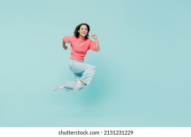 Full body young smiling happy woman of Asian ethnicity 20s wear pink sweater jump high run fast hurry up isolated on pastel plain light blue color background studio portrait. People lifestyle concept