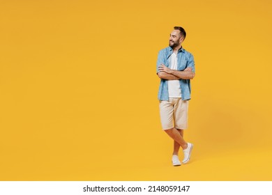 Full Body Young Smiling Happy Fun Minded Cool Man 20s Wearing Blue Shirt White T-shirt Hold Hands Crossed Folded Looking Aside On Copy Space Area Isolated On Plain Yellow Background Studio Portrait.