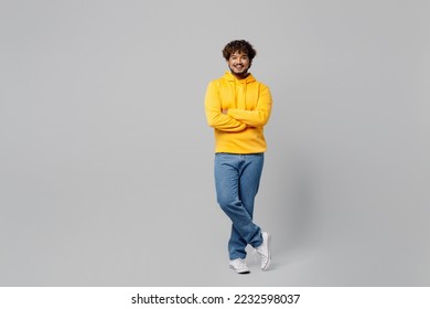 Full body young smiling happy student calm Indian man 20s with mustache and curly hair, he wear casual yellow hoody hold hands crossed folded isolated on plain grey color background studio postrait - Shutterstock ID 2232598037