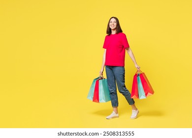 Full body young smiling happy shocked fun woman wears pink casual clothes hold in hand paper package bags after shopping walk go isolated on plain yellow background. Black Friday sale buy day concept - Powered by Shutterstock