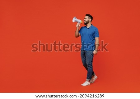 Full body young smiling happy caucasian man 20s wear basic blue t-shirt hold scream in megaphone announces discounts sale Hurry up isolated on plain orange background studio. People lifestyle concept