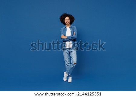 Full body young smiling happy black woman in casual clothes shirt white t-shirt hold hands crossed folded look camera isolated on plain dark blue background studio portrait. People lifestyle concept
