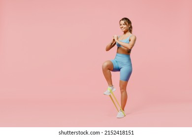 Full body young smiling sporty athletic fitness trainer instructor woman wear blue tracksuit spend time in home gym use fitness rubber bands isolated on plain pink background. Workout sport concept - Powered by Shutterstock