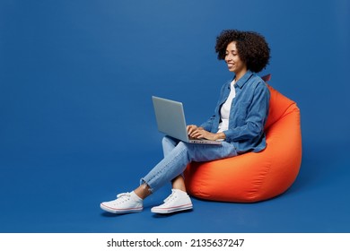 Full body young smiling student fun happy black woman in casual clothes shirt white t-shirt sit in bag chair hold use work on laptop pc computer isolated on plain dark blue background studio portrait. - Shutterstock ID 2135637247