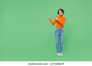 Full Body Young Smiling Woman 20s Wear Casual Orange Point Index Finger Aside On Workspace Area Mock Up Turtleneck Isolated On Plain Pastel Light Green Color Background Studio People Lifestyle Concept