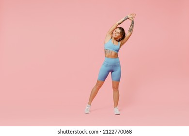 Full body young sporty fitness trainer woman wear blue tracksuit spend time in home gym tilt body to sides with hand stretch lunge exercise isolated on plain pink background. Workout sport concept.