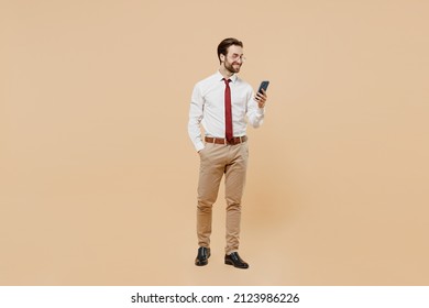 Full Body Young Successful Employee Business Man Corporate Lawyer Wear White Shirt Red Tie Glasses Work In Office Hold In Hand Use Mobile Cell Phone Isolated On Plain Beige Background Studio Portrait